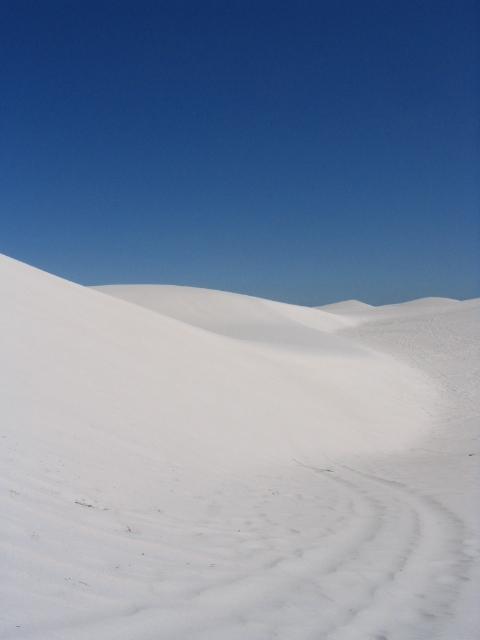 Sculpted white dune ridge rising against deep blue sky