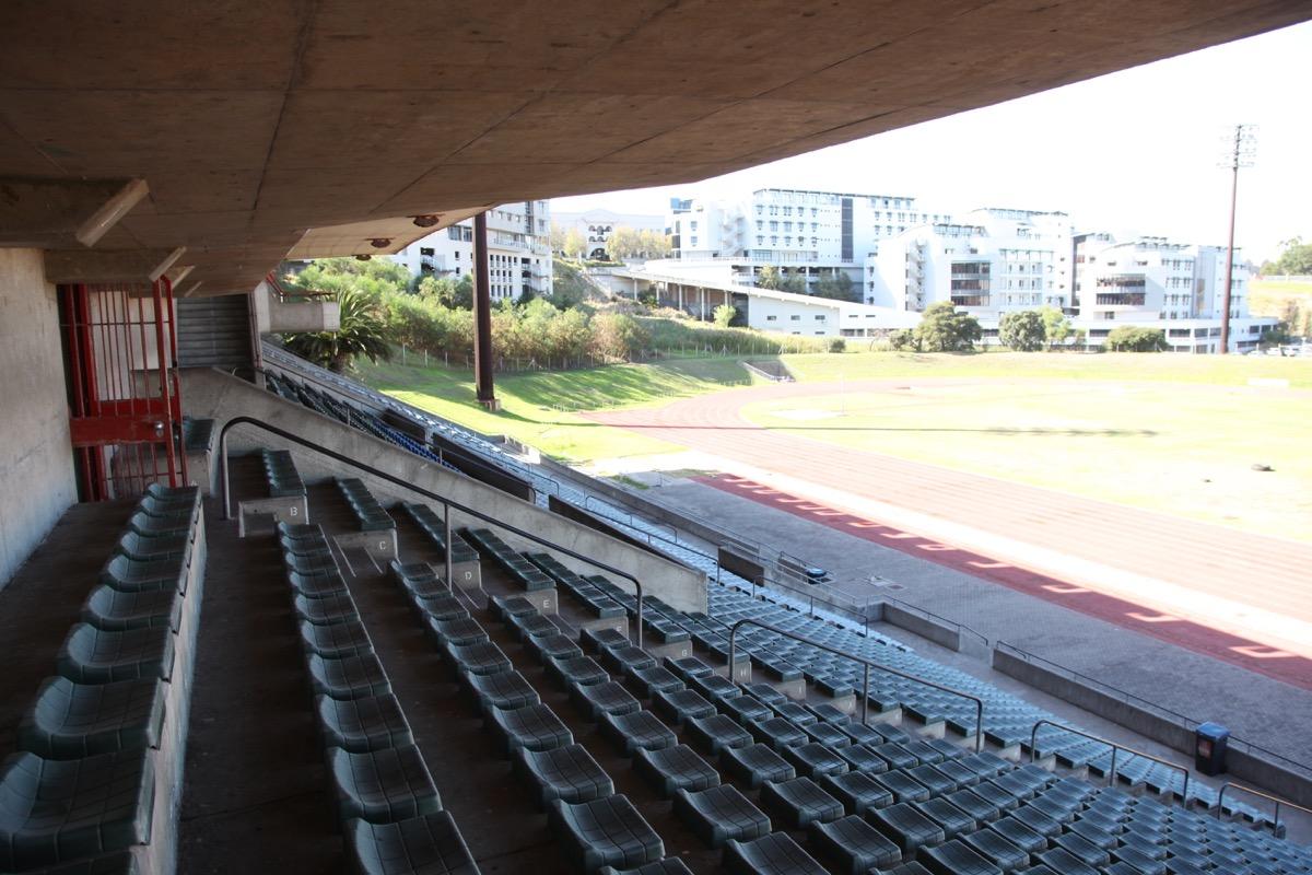 Outdoor grandstand seats overlooking an athletics track beside the velodrome