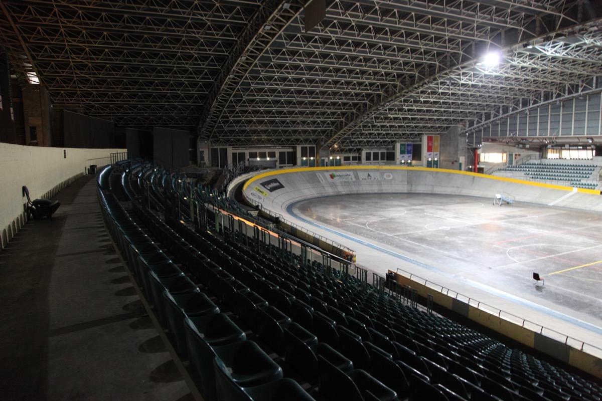Banked track and tiered seating inside the velodrome, house lights low