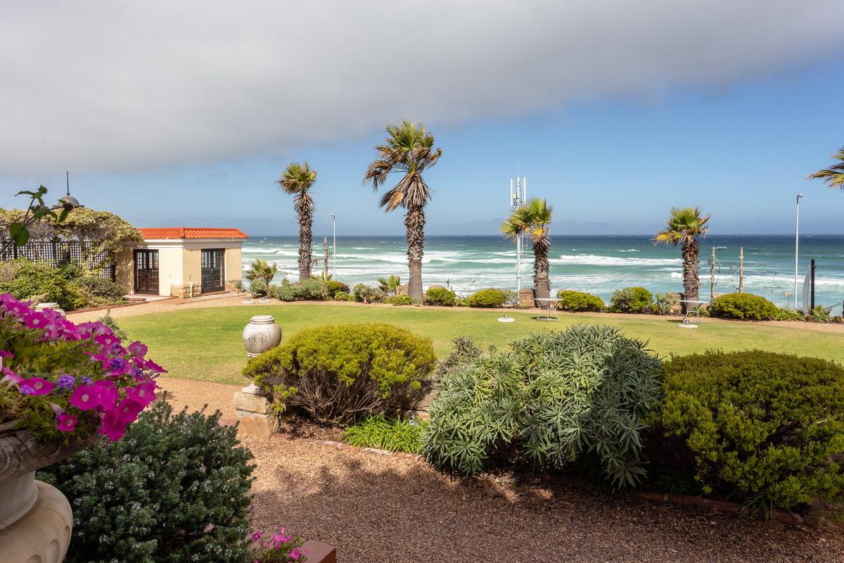 Casa Labia garden with palms and flowering shrubs, False Bay surf beyond the lawn