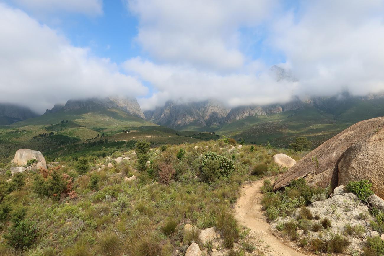 Sand track curving between boulders at Graskop with cloud on the mountain wall behind
