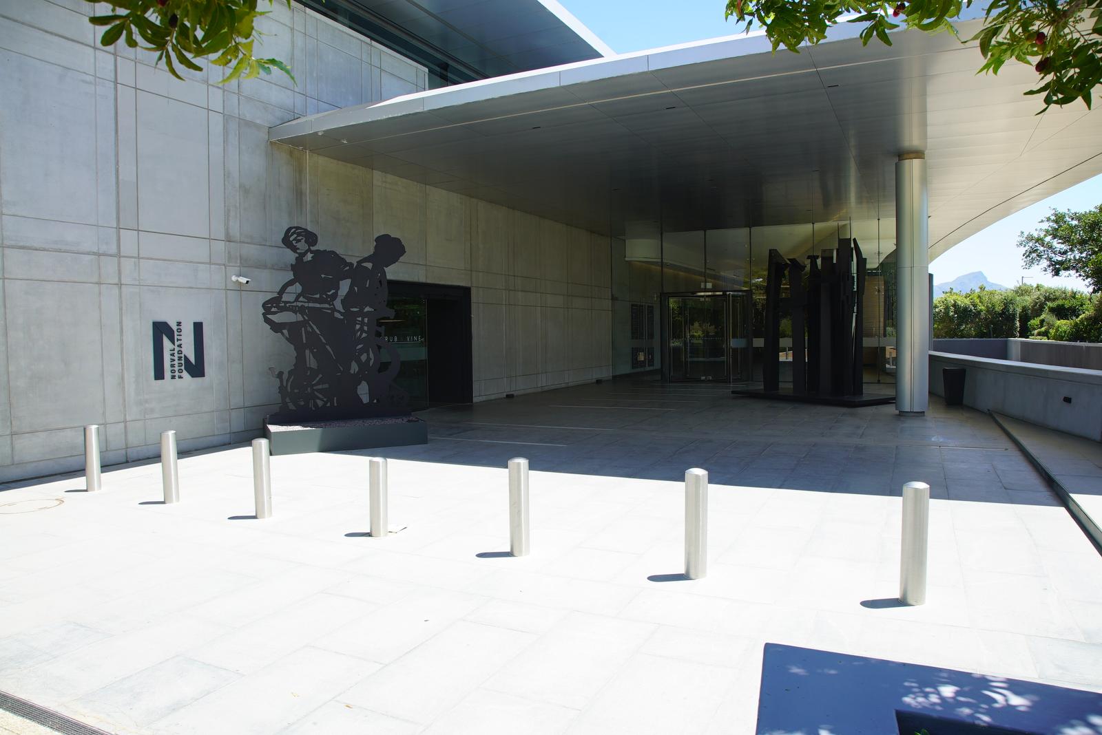 Concrete entrance plaza of the Norval Foundation with cantilevered roof, bollards and sculpture against the wall