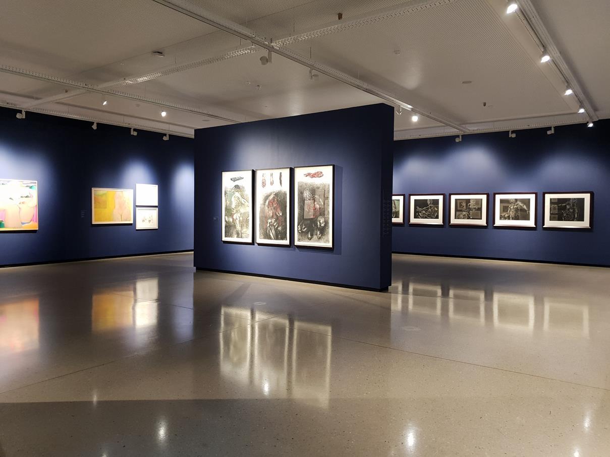 Exhibition hall with midnight-blue walls, framed works and a polished concrete floor