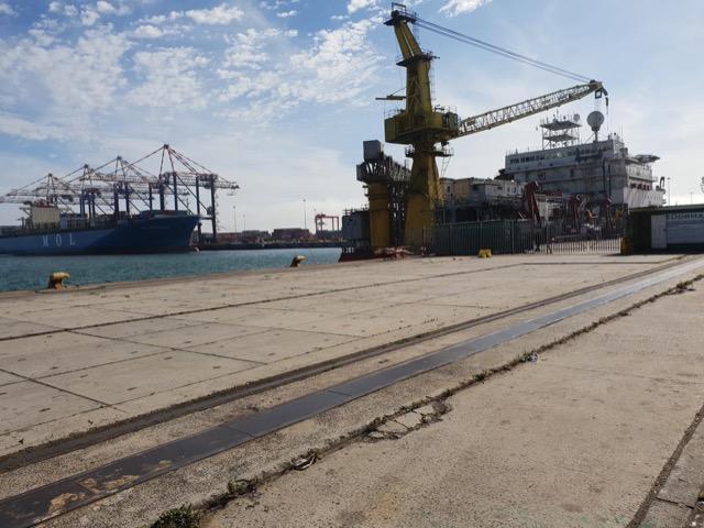 Ship-repair crane and vessel beyond a bare concrete quay apron in Cape Town harbour